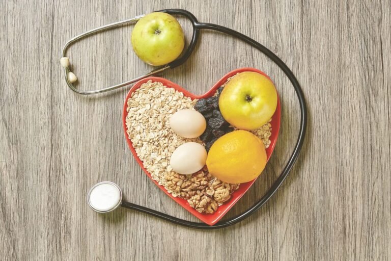 Bowl of nutritious food in a heart-shaped bowl with a stethoscope lying beside it